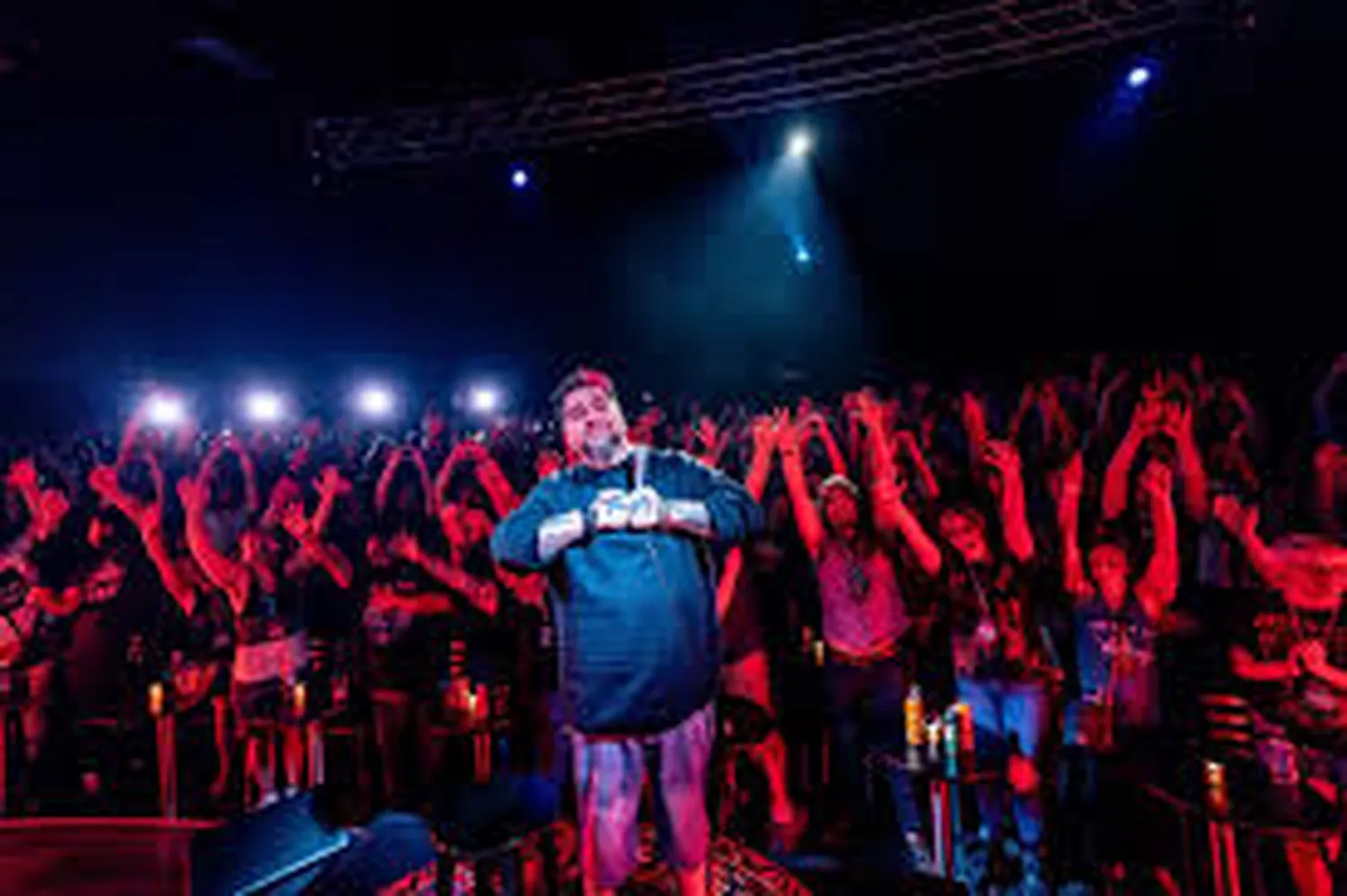 How to find stand up comedy shows near me - Crowded dark comedy club with neon stage lighting